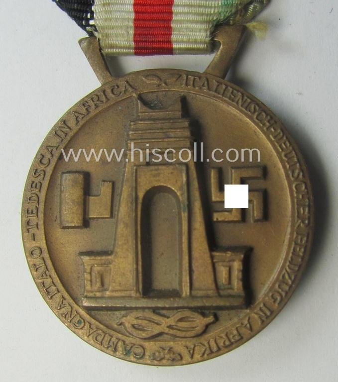 Golden-bronze-coloured- (and I deem 'Buntmetall'-based-) example of a: 'Deutsch-Italienische Feldzugsmedaille' (or: German-Italian campaign-medal) that comes mounted onto its (regular-sized) piece of original (and minimally faded!) ribbon — image 4