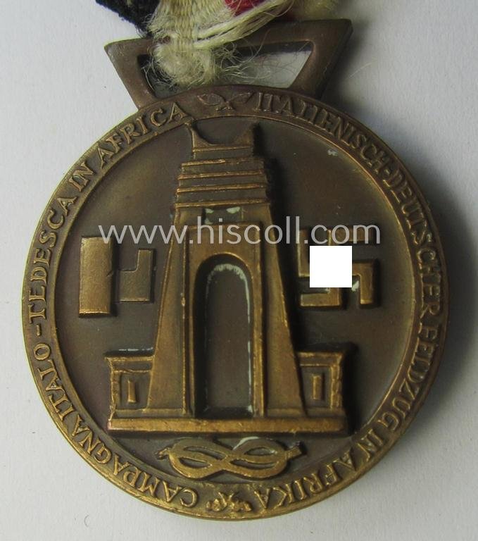 Golden-bronze-coloured- (and I deem 'Buntmetall'-based-) example of a: 'Deutsch-Italienische Feldzugsmedaille' (or: German-Italian campaign-medal) that comes mounted onto its (regular-sized) piece of original (and sun-faded!) ribbon — image 4