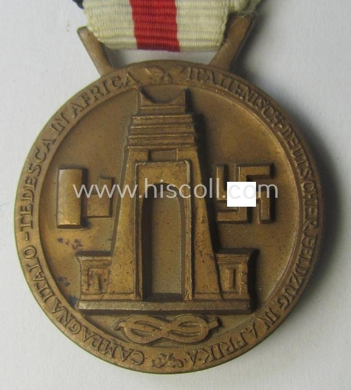 Golden-bronze-coloured- (and I deem 'Buntmetall'-based-) example of a: 'Deutsch-Italienische Feldzugsmedaille' (or: German-Italian campaign-medal) that comes mounted onto its (regular-sized) piece of original (and somewhat faded!) ribbon — image 4