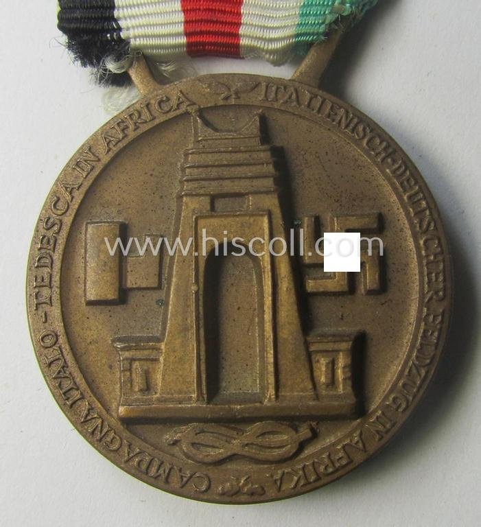 Golden-bronze-coloured- (and I deem 'Buntmetall'-based-) example of a: 'Deutsch-Italienische Feldzugsmedaille' (or: German-Italian campaign-medal) that comes mounted onto its (regular-sized) piece of original (and hardly faded!) ribbon — image 4